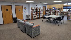 Photo of library interior with two bathrooms, tables, chairs, and shelving.