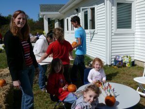 Families sitting around table outside making pumpkin crafts