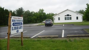 Empty parking lot with sign that reads: future home of the brunswick community library